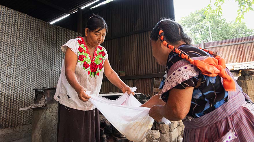 Indigenous community members preparing food together in an outdoor cooking area.