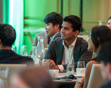 Young, recently hired employees around a table at a formal orientation event.