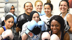 Group of people wearing boxing gloves, posing together in a gym.