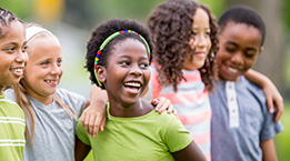 Des enfants qui sourient en se faisant un câlin. 