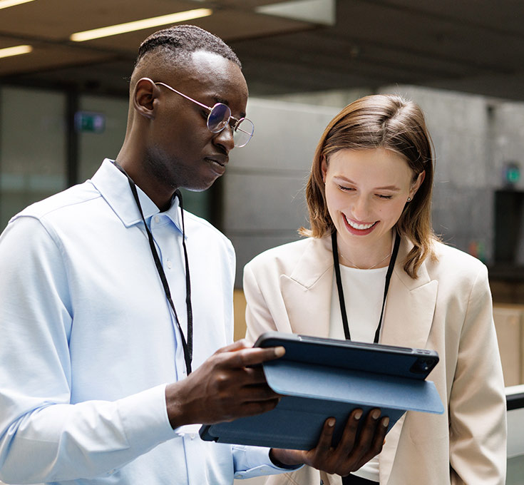 Two employees reviewing information on a tablet in an office lobby.