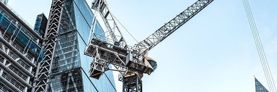 Looking upwards at a construction crane and skyscraper.