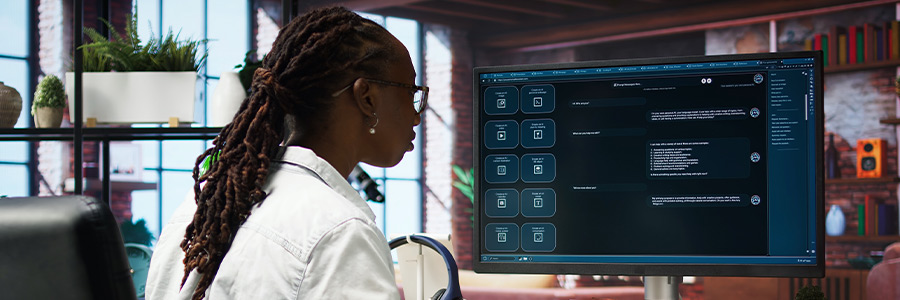 Person working at a desktop computer in a modern office, using a large monitor displaying a chat interface with multiple conversation windows.