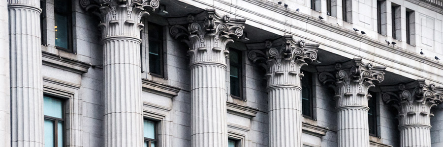 Row of classical stone columns with ornate capitals on a historic building façade.