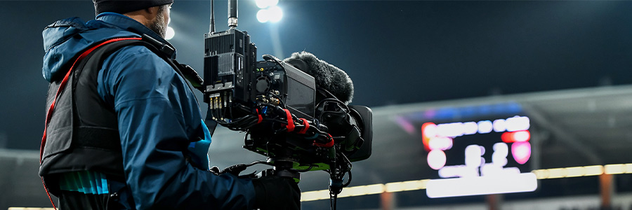 TV camera operator filming at a sports stadium.