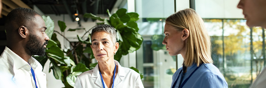 Healthcare professionals in discussion, reviewing notes in a bright clinic or hospital setting.