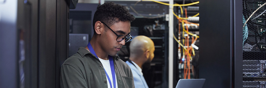 IT professionals working with laptops in a data center.