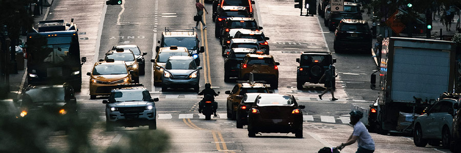 Vehicles travelling on a multi-lane highway at sunset, with dense traffic and warm light.