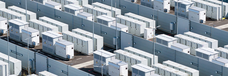 Rows of industrial battery storage units arranged in a grid at a power facility.