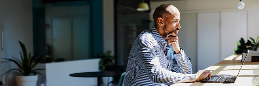 Person working on a laptop at a desk in a bright office.