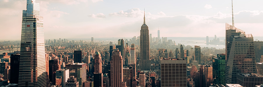 Panoramic view of the Manhattan skyline with the Empire State Building and surrounding skyscrapers under a partly cloudy sky.