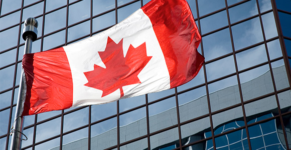 Canadian flag waving in front of a corporate building