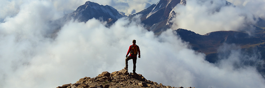 Un homme debout sur le sommet d’une montagne qui regarde le paysage.