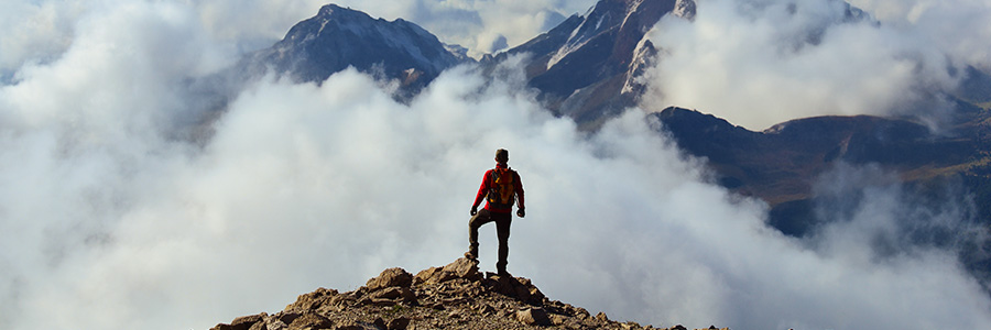 A man standing on a mountaintop looking at the landscape