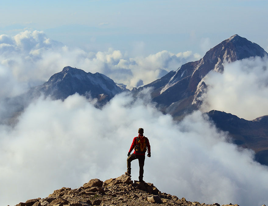 A man standing on a mountaintop looking at the landscape
