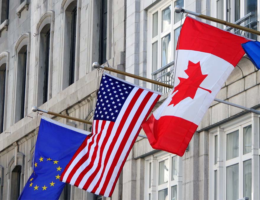 European Union, American and Canadian flags flying outside of an office building 
