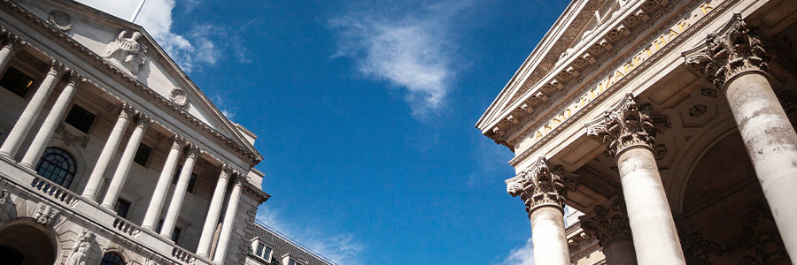 The Bank of England building facing the Royal Exchange under a blue sky.