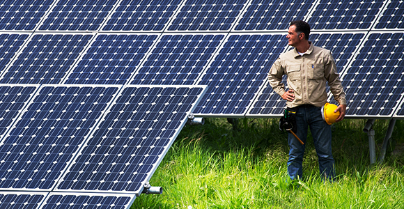 Un homme debout devant des rangées de panneaux solaires. 