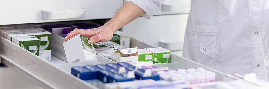 Un pharmacien regarde dans un tiroir qui contient différents médicaments.