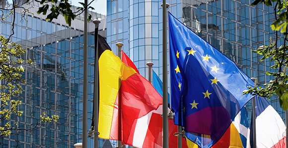 Flags from different countries waving in front of corporate buildings.