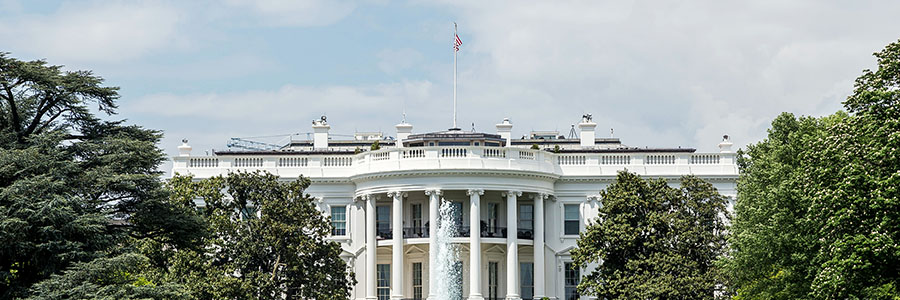 The White House building in Washington D.C. with a fountain and lawn in front.