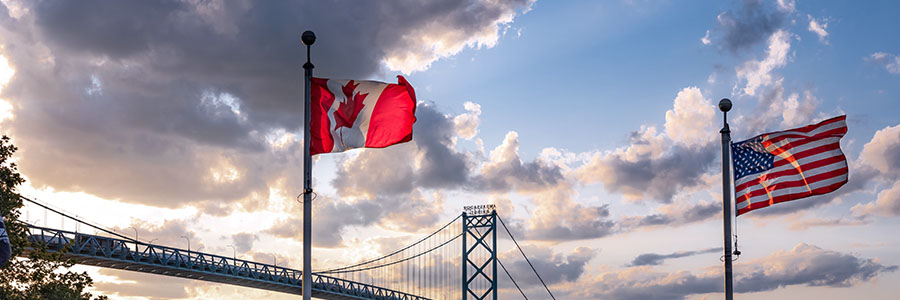 Canadian and U.S. flags with the Ambassador Bridge in the background.