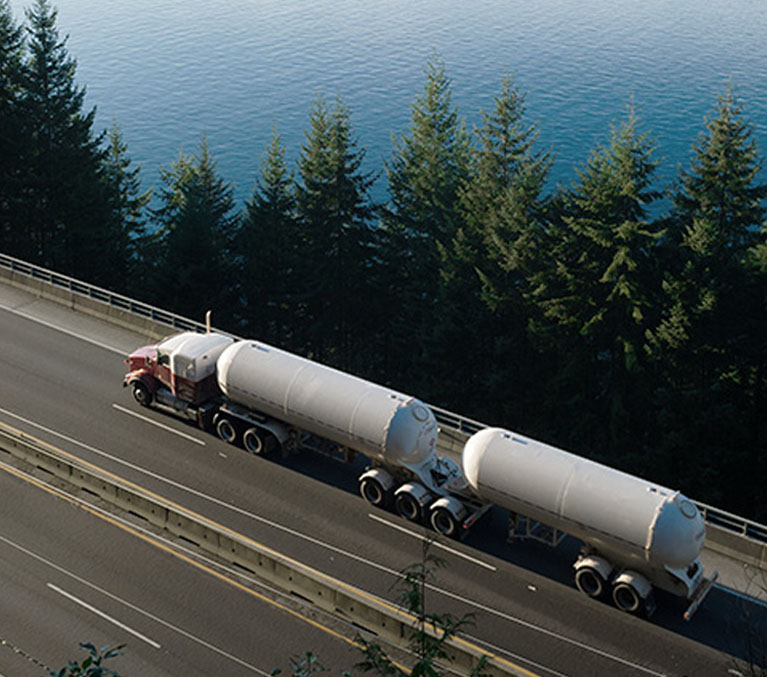 Un camion transportant de l’hydrogène sur une autoroute entourée de lacs et de collines