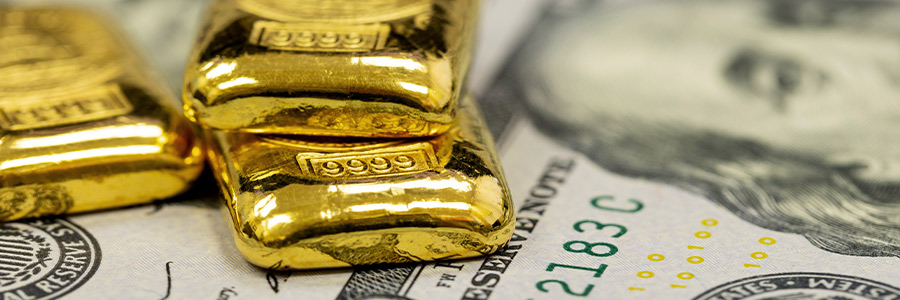 Gold bars positioned on top of U.S. currency.