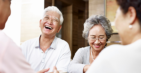 Un couple de personnes âgées sourit et rit avec des amis.