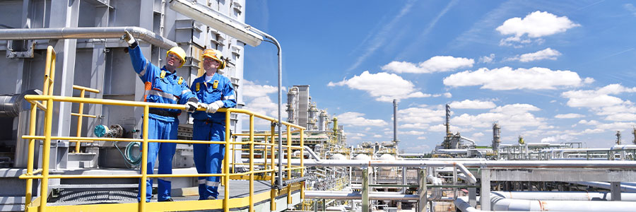 Two industrial workers outside an oil processing refinery