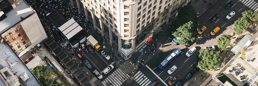 Aerial view of a busy downtown intersection with traffic, pedestrians, and surrounding city buildings.