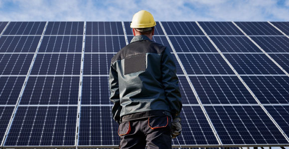 A man standing in front of rows of solar-panels.