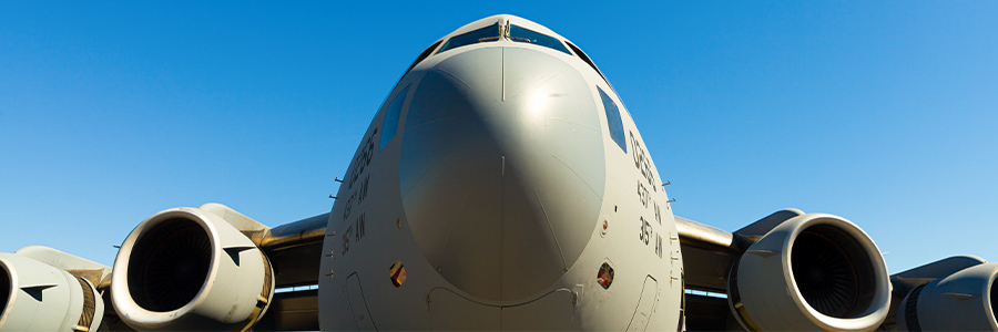 Front view of a military cargo aircraft against a clear blue sky.