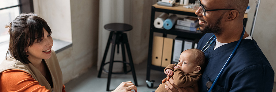 Parent and healthcare professional holding an infant during a pediatric checkup.