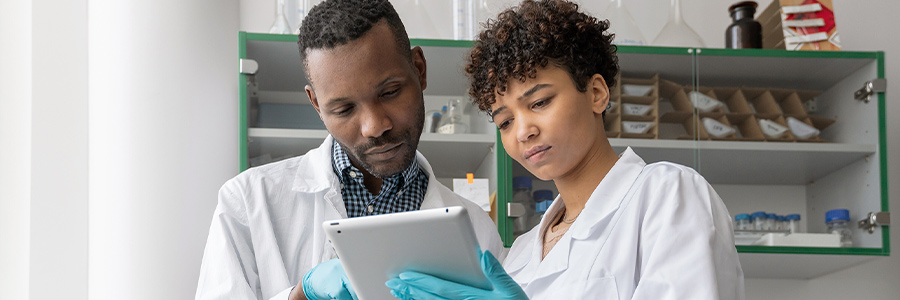 Two laboratory researchers reviewing data on a tablet in a lab.