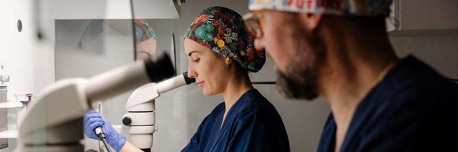 People in protective laboratory clothing using microscopes and handling samples in a research lab
