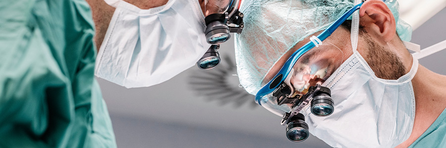 Close-up of medical professionals wearing surgical masks and magnifying loupes during a procedure.