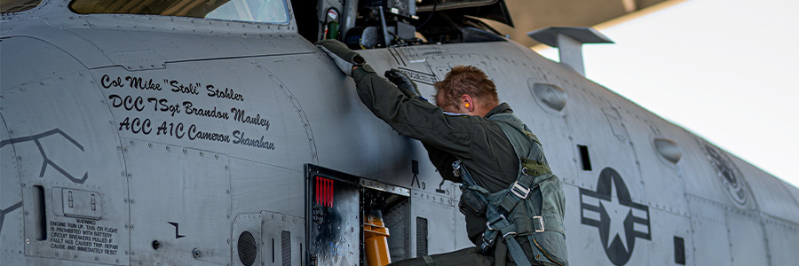 An Air Force pilot climbing into a U.S. military aircraft beside the cockpit.