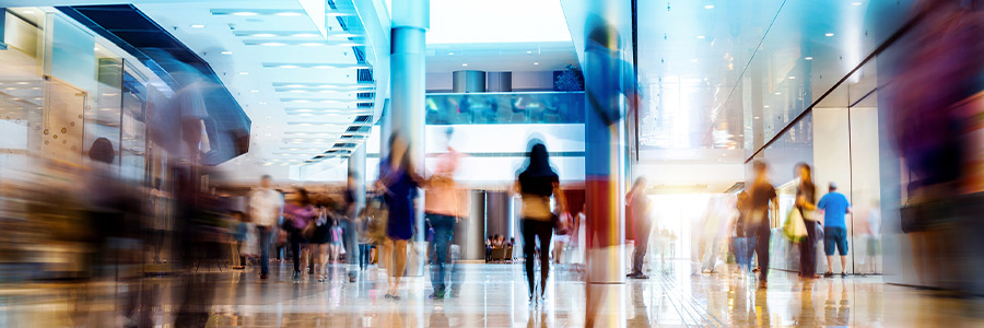 Busy shopping mall interior with people walking and bright lighting.