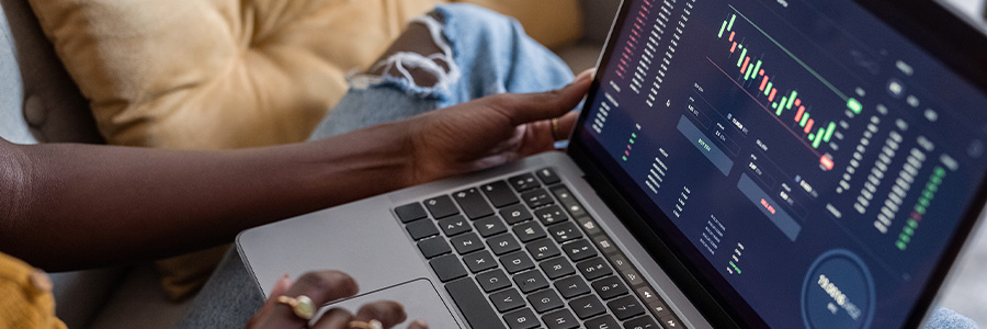 Person using a laptop to monitor financial market data and trading charts.
