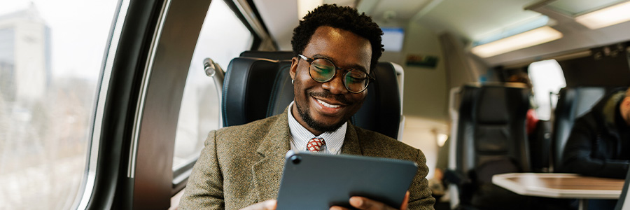 Person wearing a suit using a tablet computer while on a passenger train.