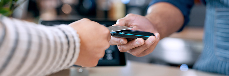 Close up of hands where a person is making a contactless payment with a smartphone in a retail store.