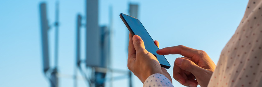 A person using a smartphone with cell towers in the background.