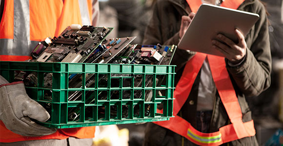 Des travailleurs tiennent des cartes mères et des déchets électroniques qui seront réutilisés.