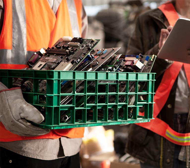 Workers holding motherboards and electronic waste to be reused