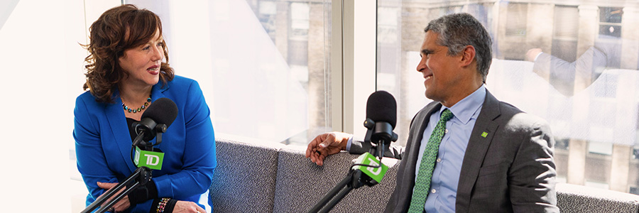 Two speakers seated with microphones during a podcast recording.