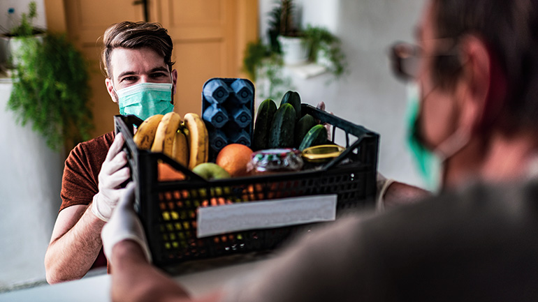 A man wearing a protective mask delivers a basket of food.