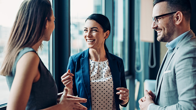 Three corporate professionals chatting in a boardroom