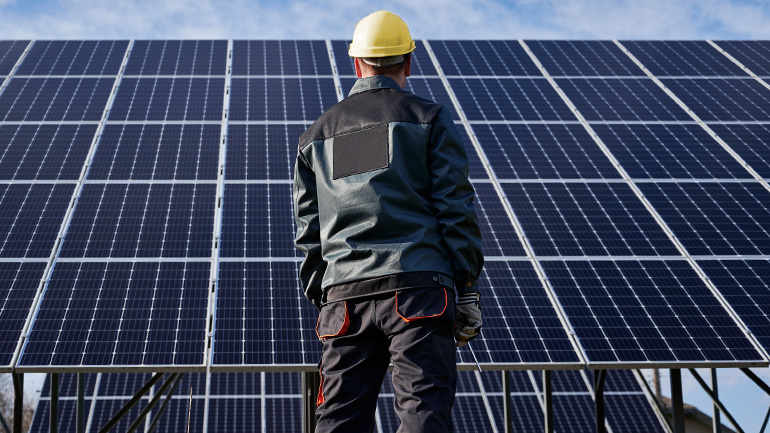 A man standing in front of rows of solar-panels.