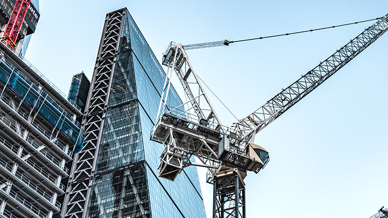Looking upwards at a construction crane and skyscraper.